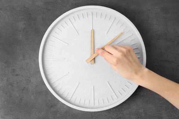 man setting time on a wall clock