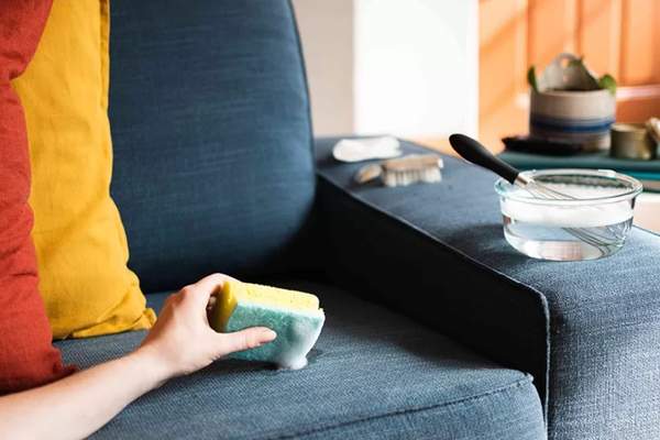 Using dish soap to clean spots on couch.