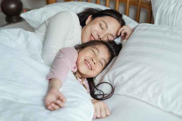 An woman and her girl laying on a bed