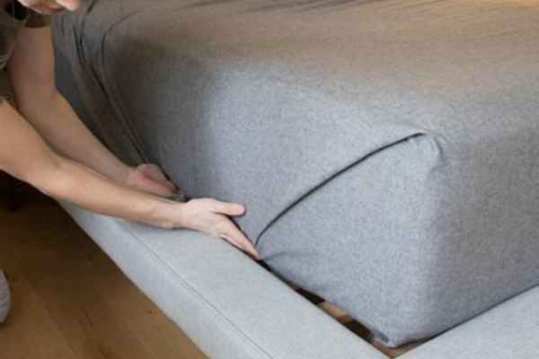 tucking the corners of a non fitted sheet on a bed